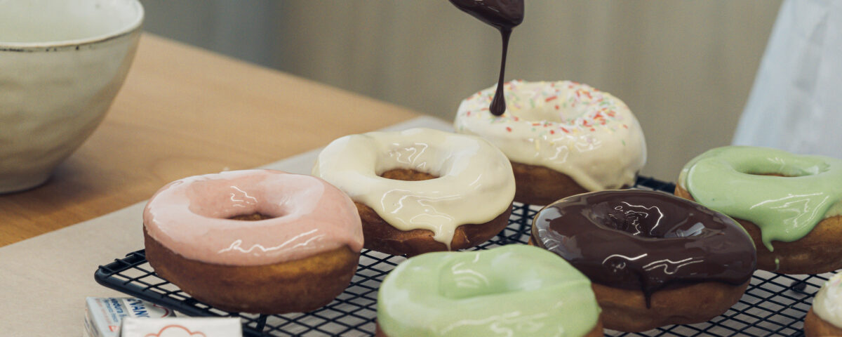 Donuts glaseados de colores sobre una rejilla de horno al lado de un paquete de levadura fresca Levanova