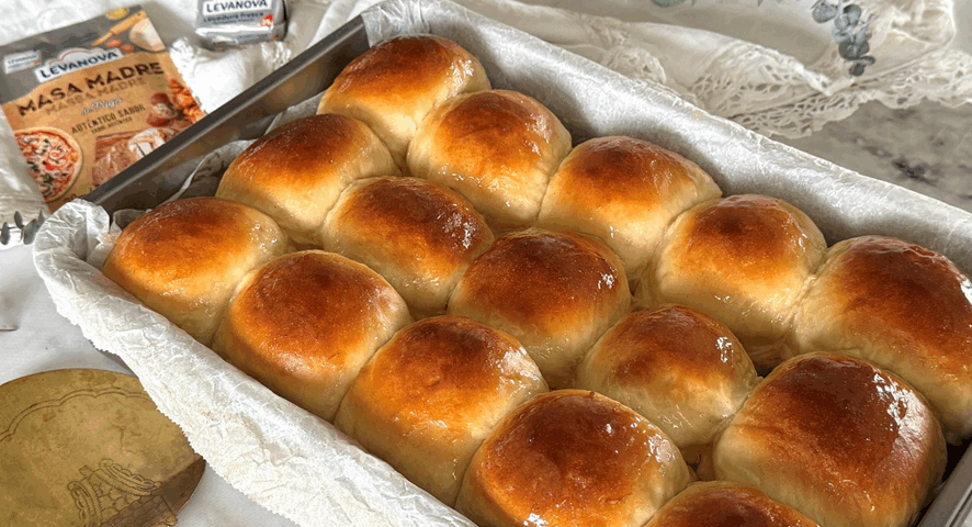 Una bandeja de horno repleta de bollos hawaianos dorados y brillantes