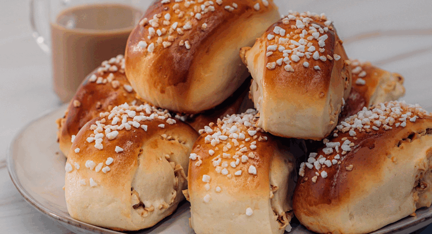 Bollitos de brioche dorados decorados con azúcar perlado en la parte superior, mostrando un relleno de avellana en los laterales