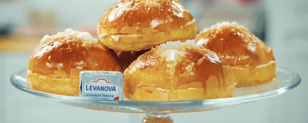 Cuatro bollitos de mantequilla de Bilbao dorados sobre un soporte de cristal, junto a un paquete de levadura fresca Levanova