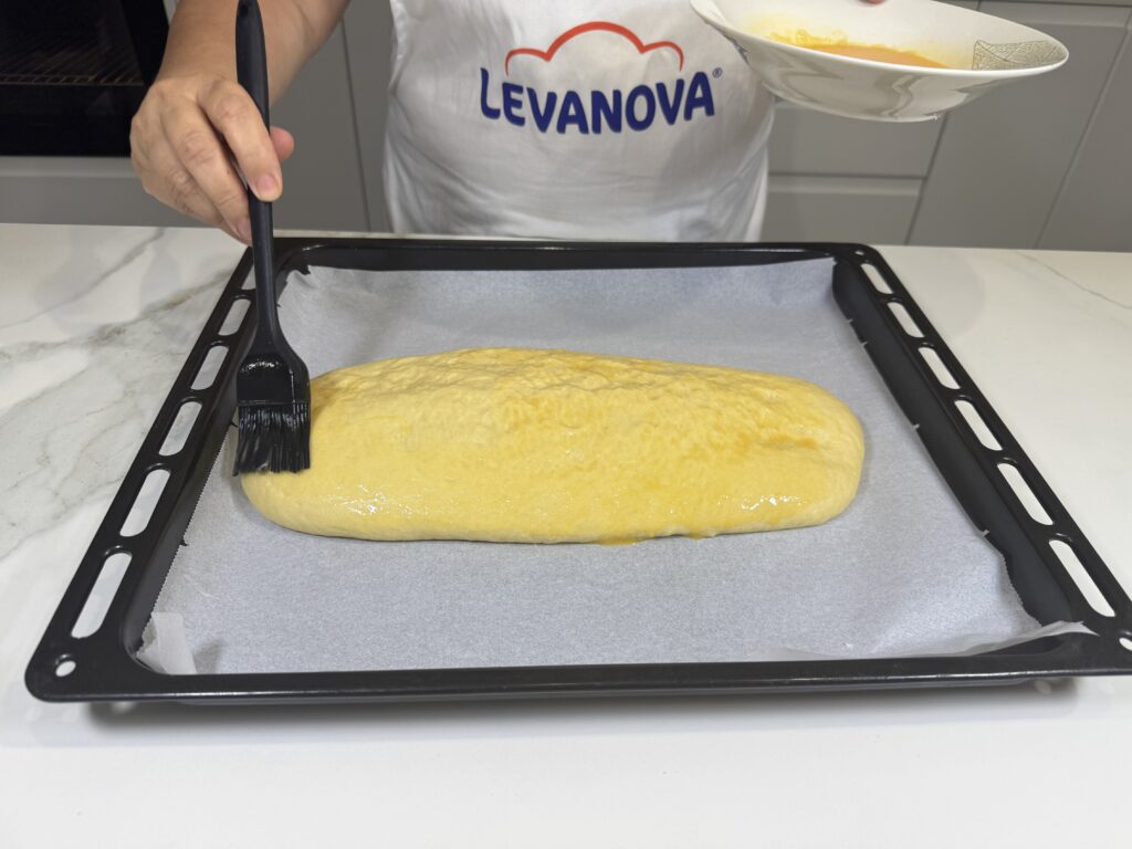 Pintando la superficie de la coca con huevo batido antes de hornear