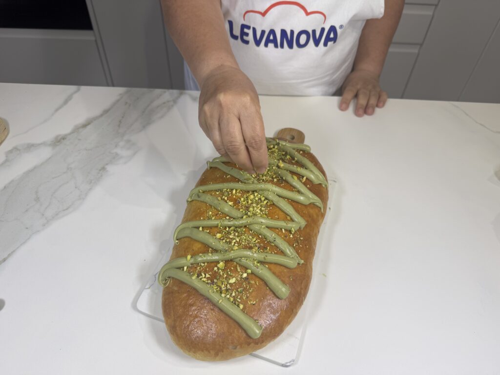 Decorando la Coca de San Juan horneada con crema y pistachos picados