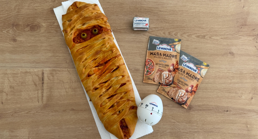 Pizza de Halloween con forma de momia, decorada con aceitunas como ojos y acompañada de productos de masa madre Levanova